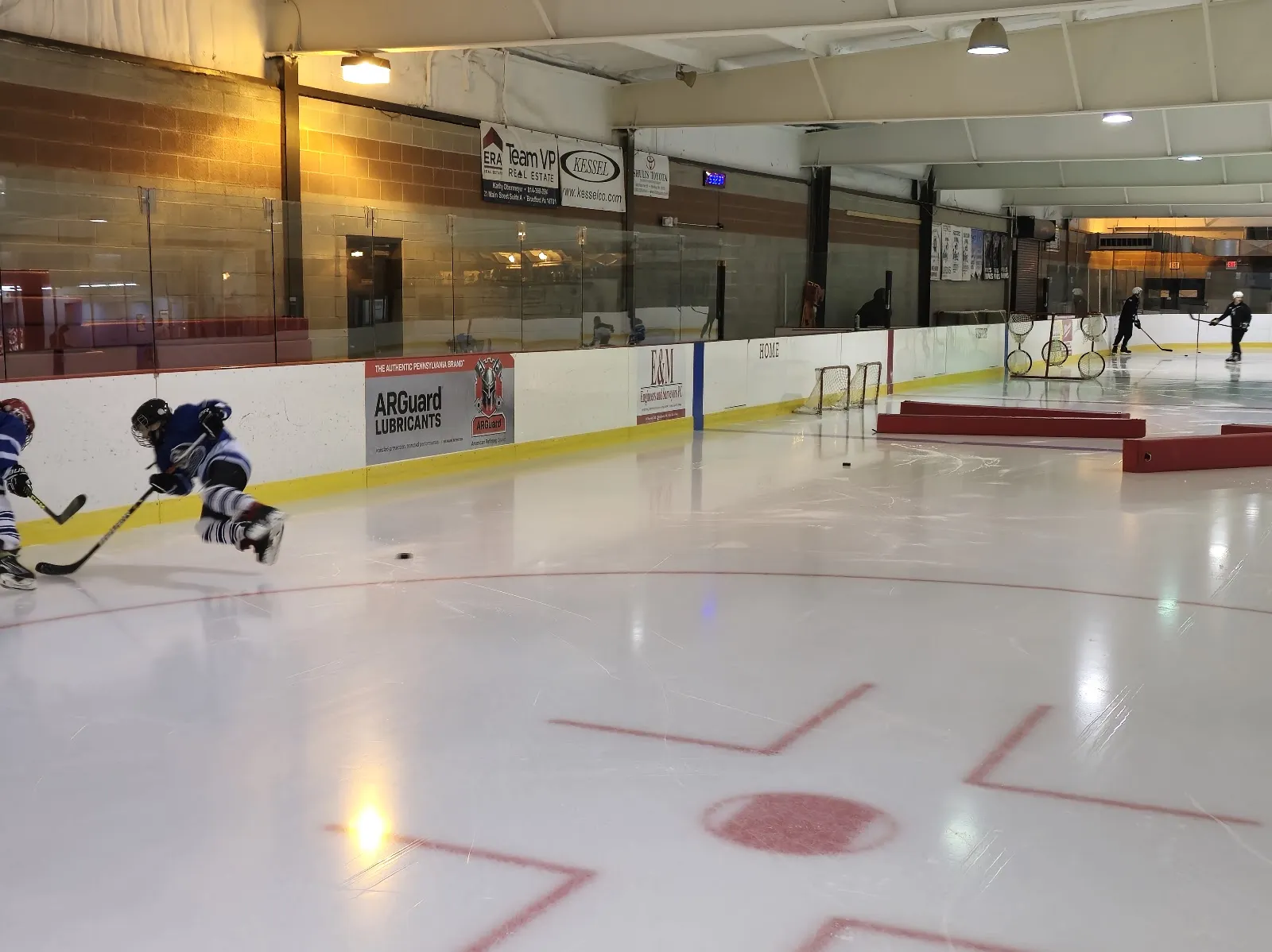 Youth hockey on the ice at Callahan Park's rink, seen along the boards — Callahan Ice Rink