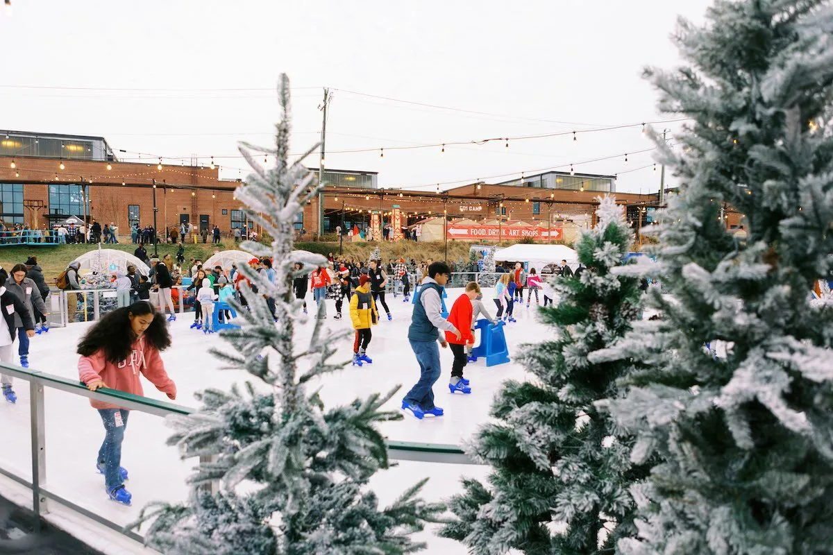 Skaters on the Camp North Pole ice with the Camp North End building behind (Camp North End website) — Camp North Pole Ice Skating