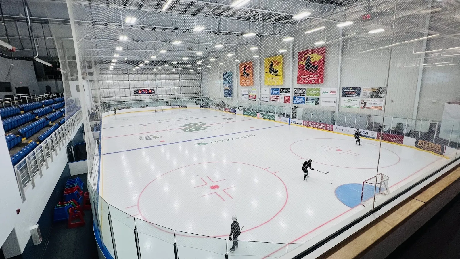 Arena del Canada Games Centre: una pista de hielo vista desde las gradas con unos cuantos patinadores — Canada Games Centre