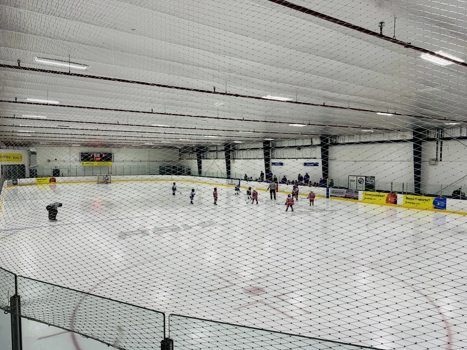 Rink 3 at the Entripy Centre in Oakville, seen from above through the safety netting during a youth game — Entripy Centre - Oakville
