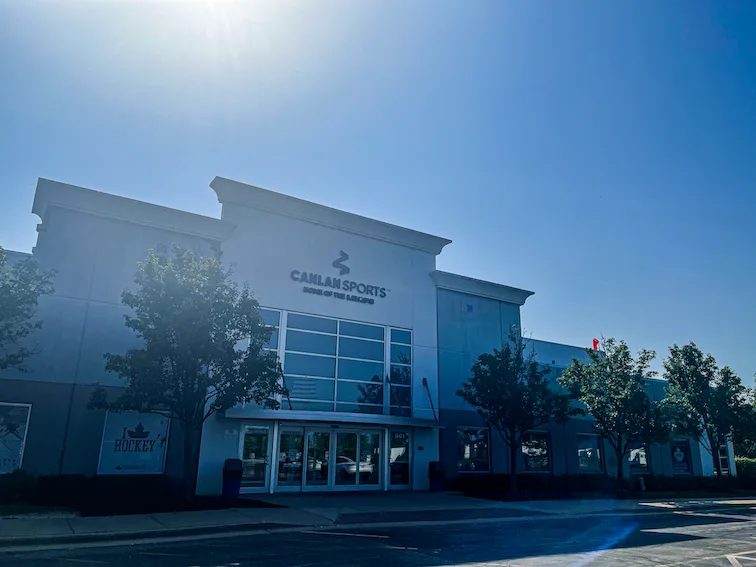 Pale stucco and the corner tower, shot into the afternoon sun — Canlan Sports West Dundee