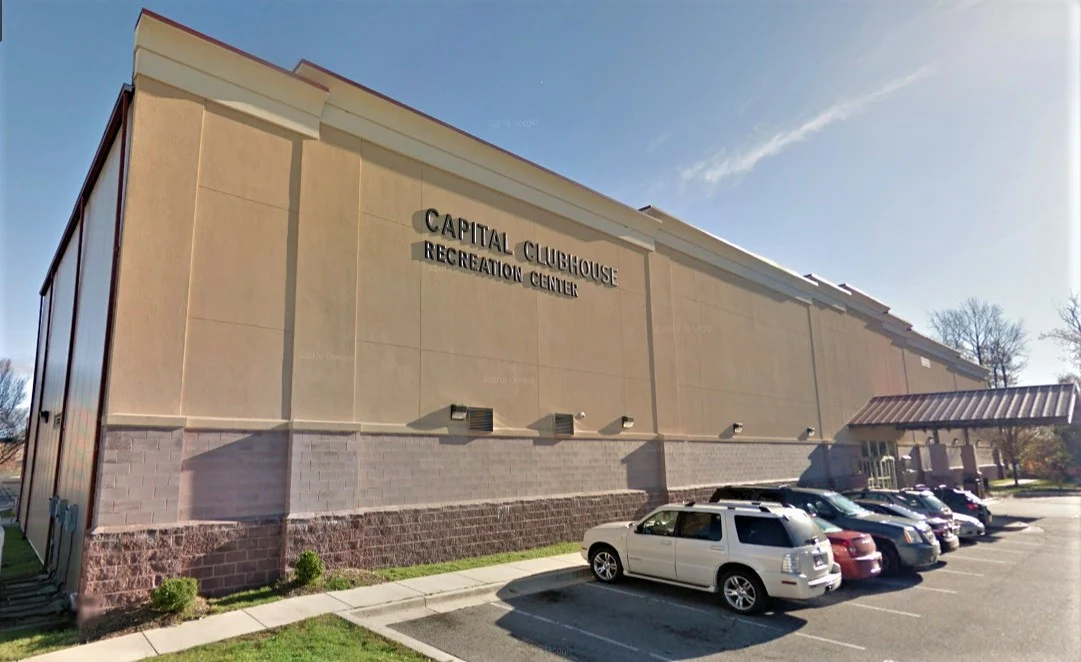 El muro exterior con el nombre de Capital Clubhouse y el estacionamiento junto al edificio. — Capital Clubhouse