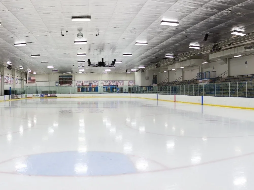Empty, freshly flooded ice photographed low from one end — Carlson Ice Arena