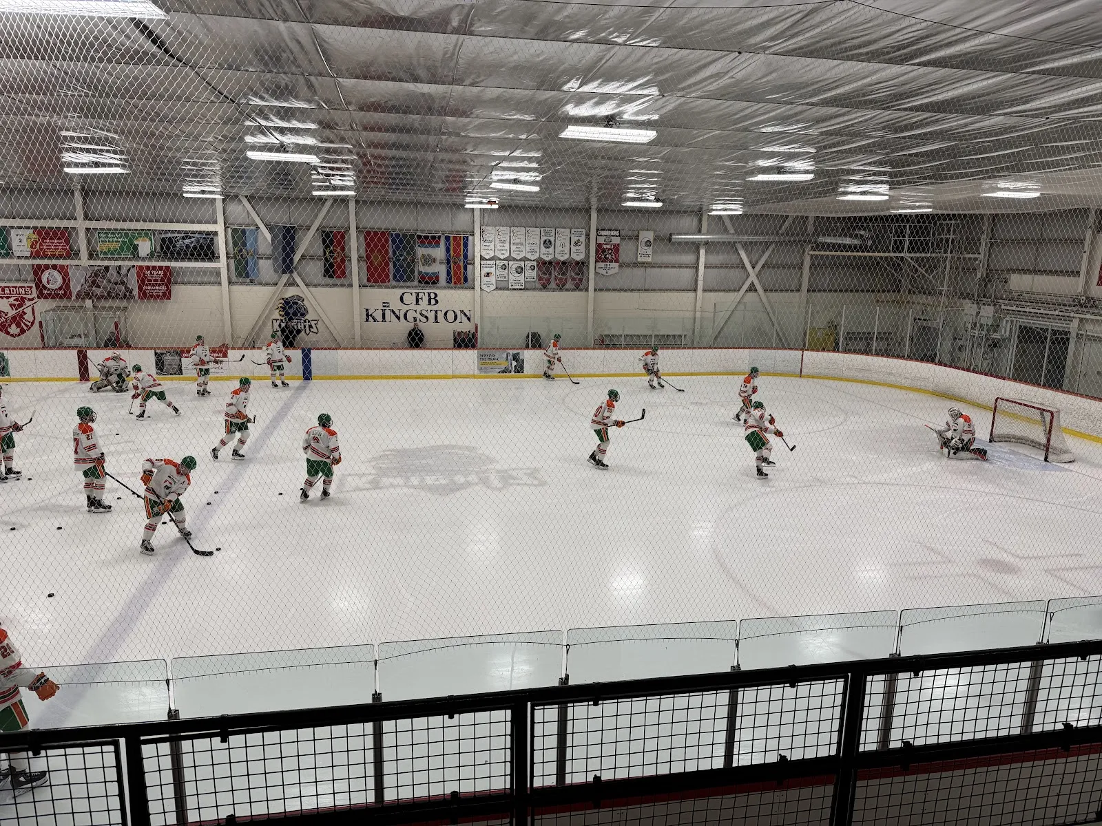 Players warming up on the ice at Centre 70 Arena, seen from the rink-side walkway — Centre 70 Arena