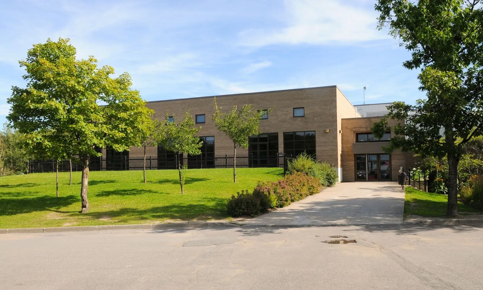 Le Centre communautaire Michel-Labadie, en brique beige, à Québec, vu de l’autre côté de sa pelouse avant par une journée d’été — Centre communautaire Michel-Labadie