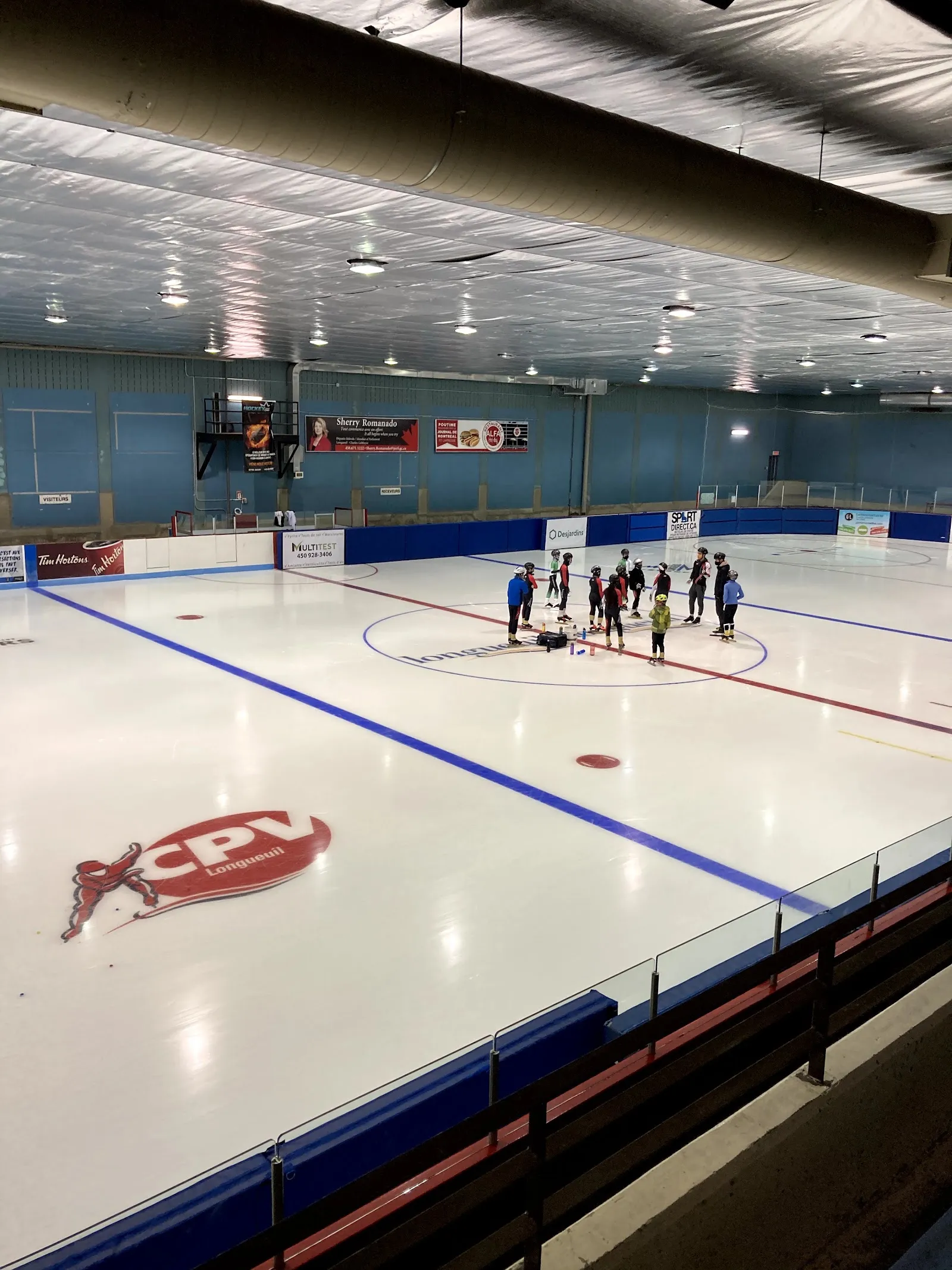 Patinadores sobre el hielo en el Aréna Olympia, con el logotipo del club de patinaje de velocidad en el hielo. — Centre Olympia