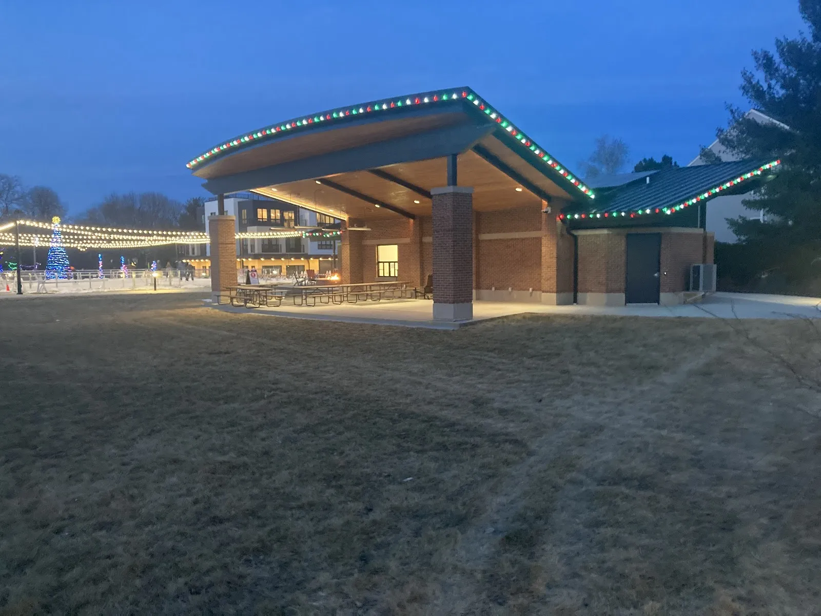 The lit pavilion at Century School Park in Verona at dusk, with the string-lit rink beyond — Century School Park Ice Rink