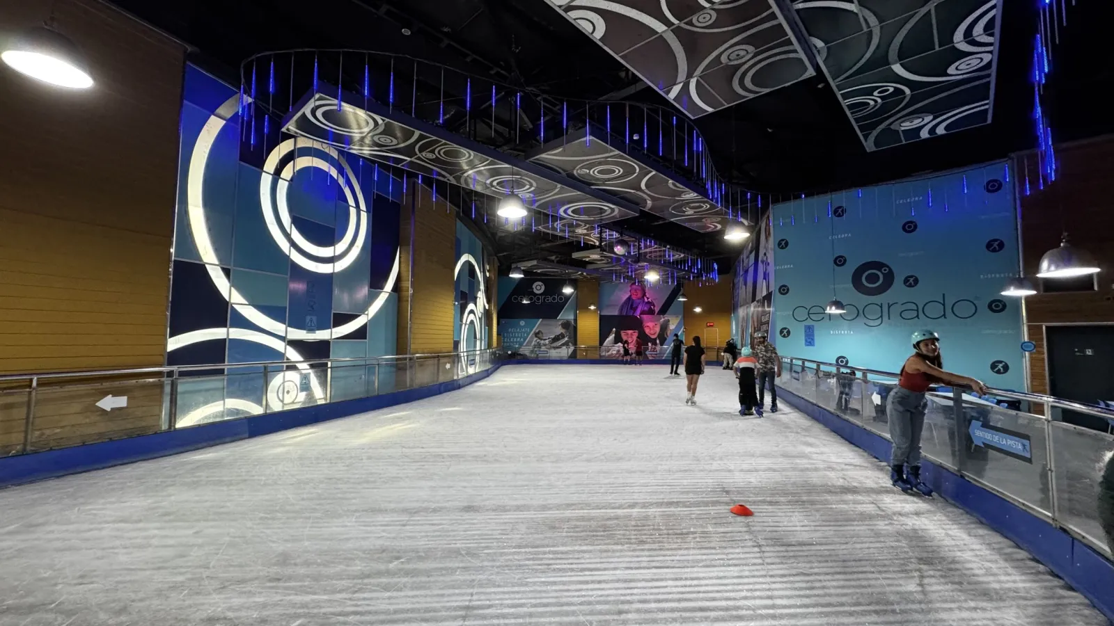 A curve of the ice sheet inside Mall Arauco Maipú, with the blue Cerogrado wall beyond the rail — Cerogrado Mall Arauco Maipú