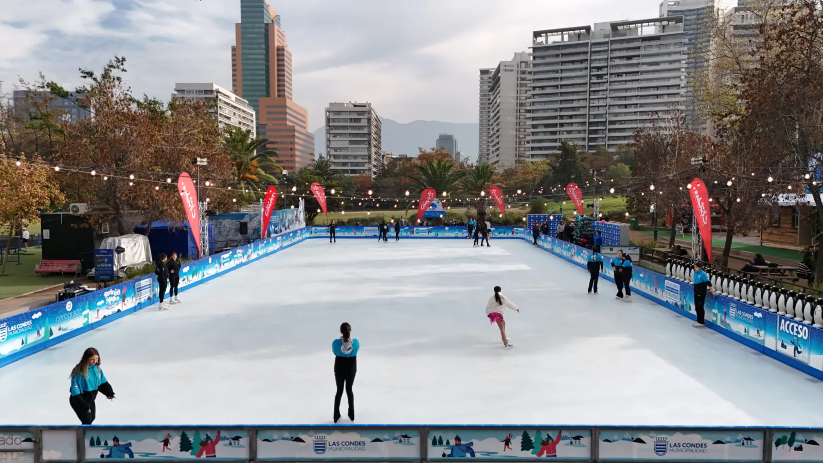 The open-air ice rink in Parque Araucano by day, with the Las Condes towers and the Andes behind the boards — Cerogrado Parque Araucano (Las Condes)