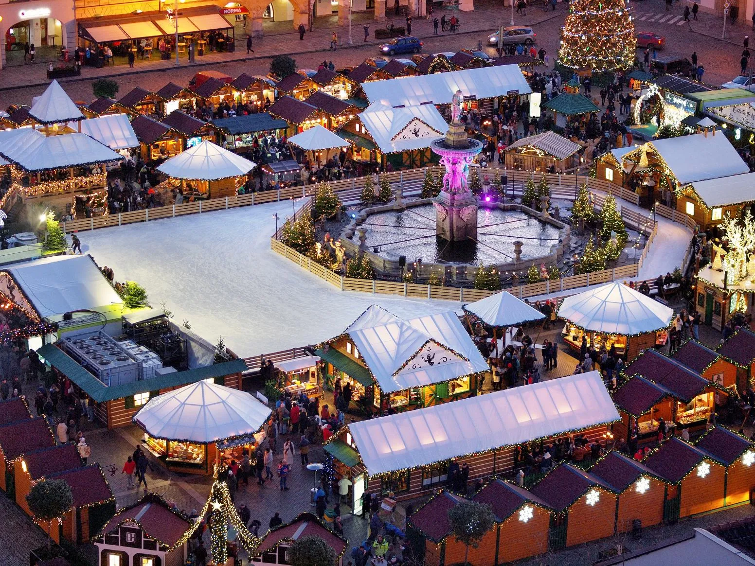 Aerial view of the Christmas market in České Budějovice, with the skating rink laid out among the market stalls beside the fountain. — Českobudějovické adventní kluziště (České Budějovice)