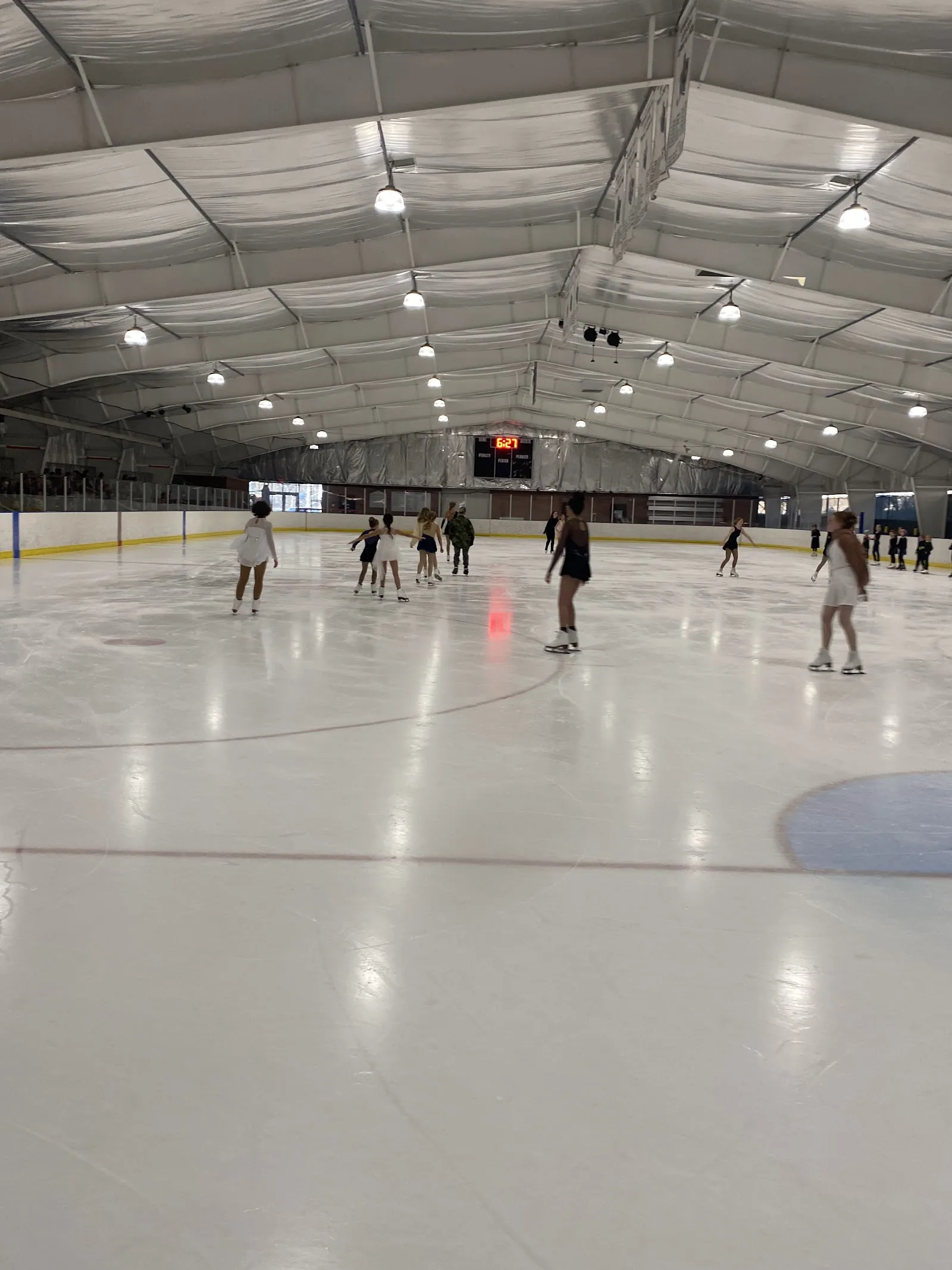 Patinadores del público en la pista bajo el techo arqueado aislado, con el marcador en el extremo opuesto. — Chapman Hill Ice Rink