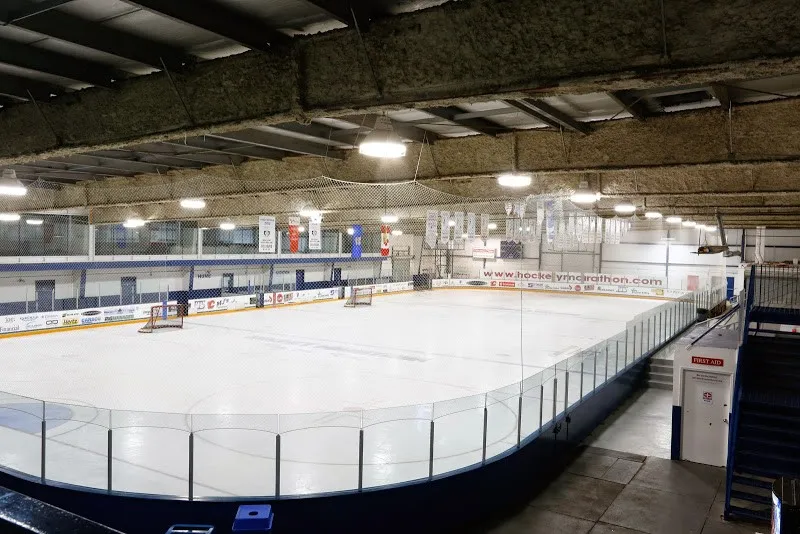 La pista de hockey vacía del Chestermere Recreation Centre vista desde la grada, con el cristal, las vallas y un techo de acero — Chestermere Recreation Centre