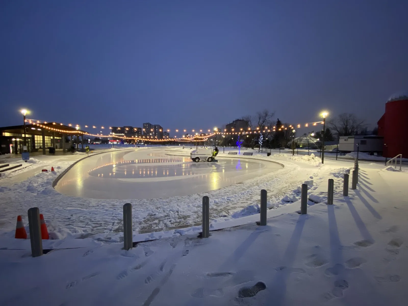 El hielo iluminado de la pista de patinaje de Chinguacousy Park al atardecer, con bancos de nieve y tiras de luces — Chinguacousy Park Skating Trail