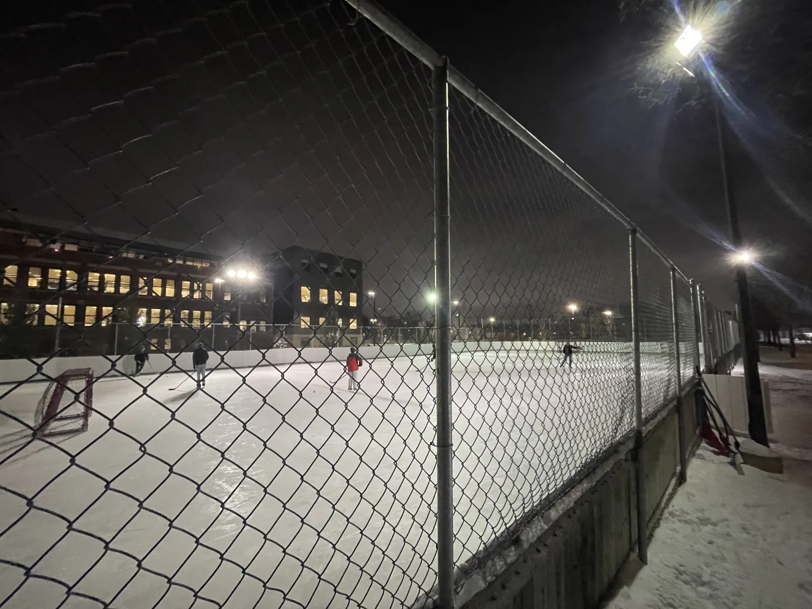 City Park outdoor rink at night, fenced rink beside City Park Collegiate (City Park Community Association rink page) — City Park Outdoor Rink (Saskatoon)