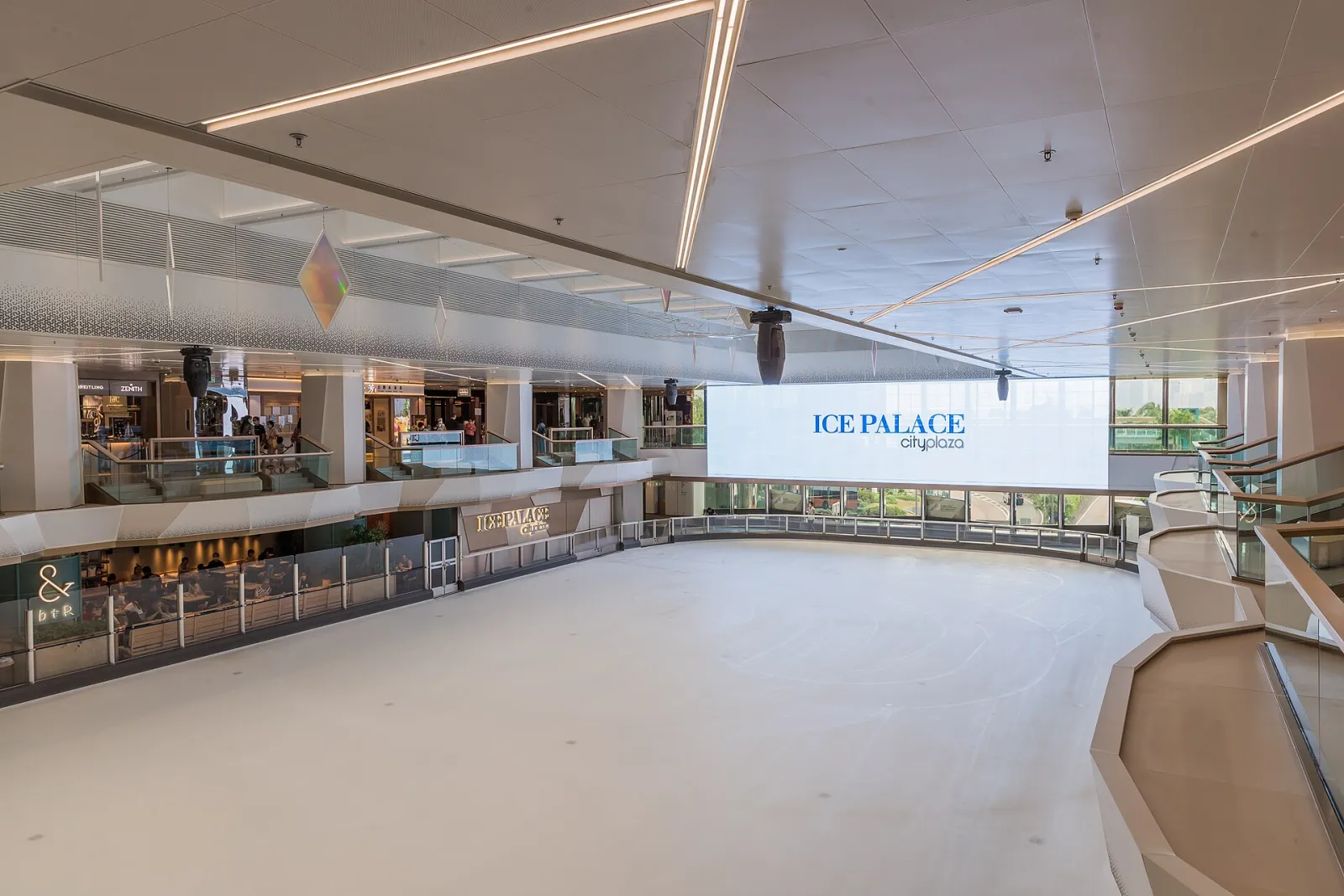 The empty ice at Cityplaza Ice Palace after its renovation, with the Ice Palace screen at the far end and the rink-side restaurants along the glass. — Cityplaza Ice Palace