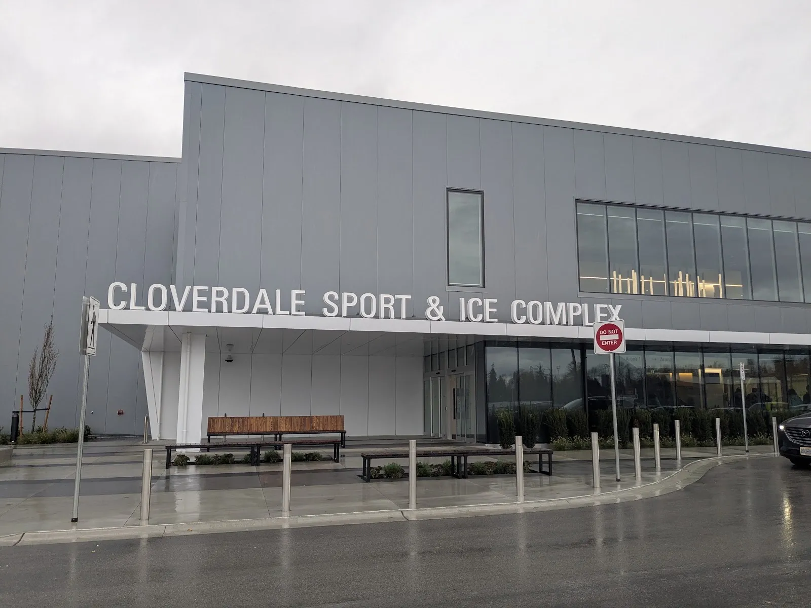 The Cloverdale Sport & Ice Complex entrance, its name in large white letters above a canopy on a tall grey-clad building — Cloverdale Sport & Ice Complex