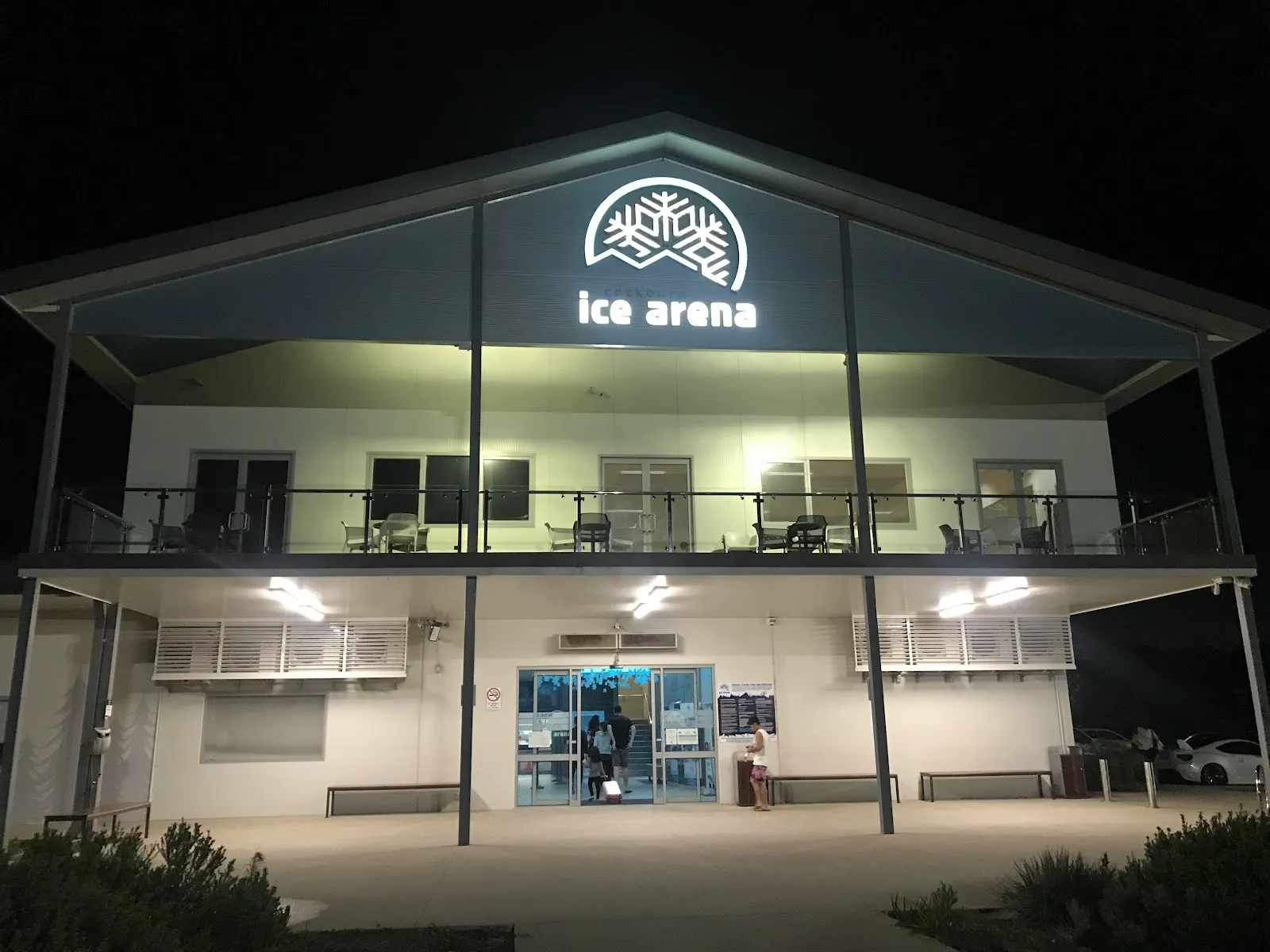 The front of Cockburn Ice Arena at night, with its entrance and sign — Cockburn Ice Arena