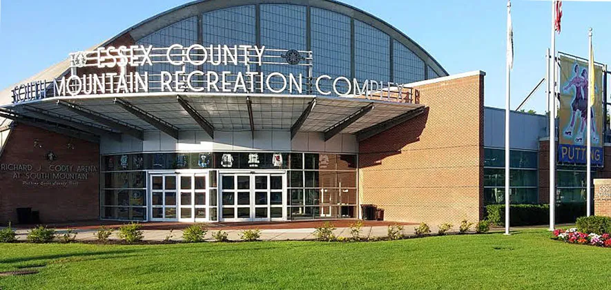 Entrada principal del Essex County South Mountain Recreation Complex, con una marquesina que dice "Richard J. Cody Arena at South Mountain" sobre las puertas de vidrio y letreros del condado de Essex en la línea en arco del techo. — Essex County Richard J. Codey Arena
