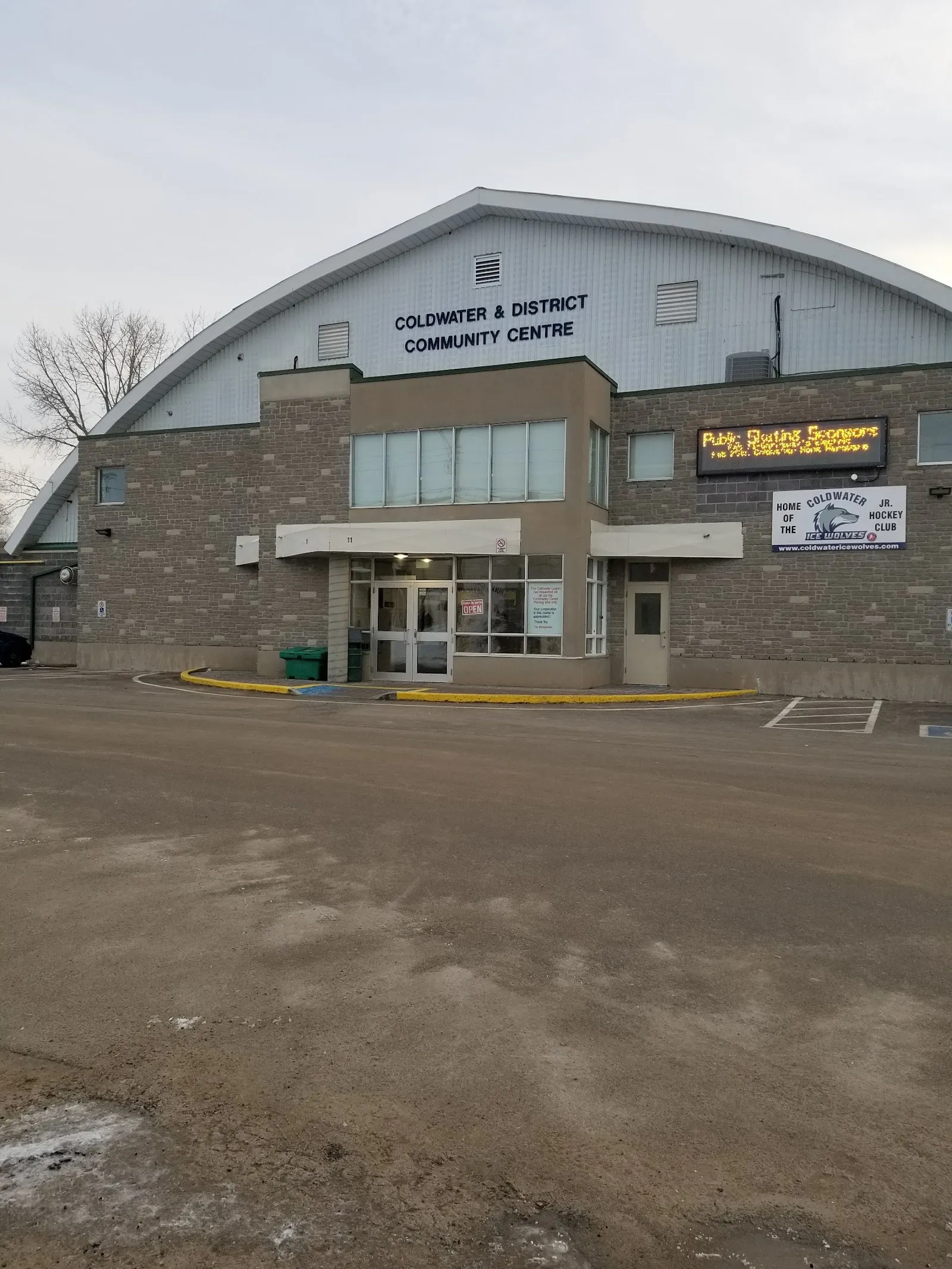 El Coldwater and District Community Centre, una fachada de piedra con su nombre en el techo arqueado de la arena y un letrero de Home of the Ice Wolves. — Coldwater Community Centre