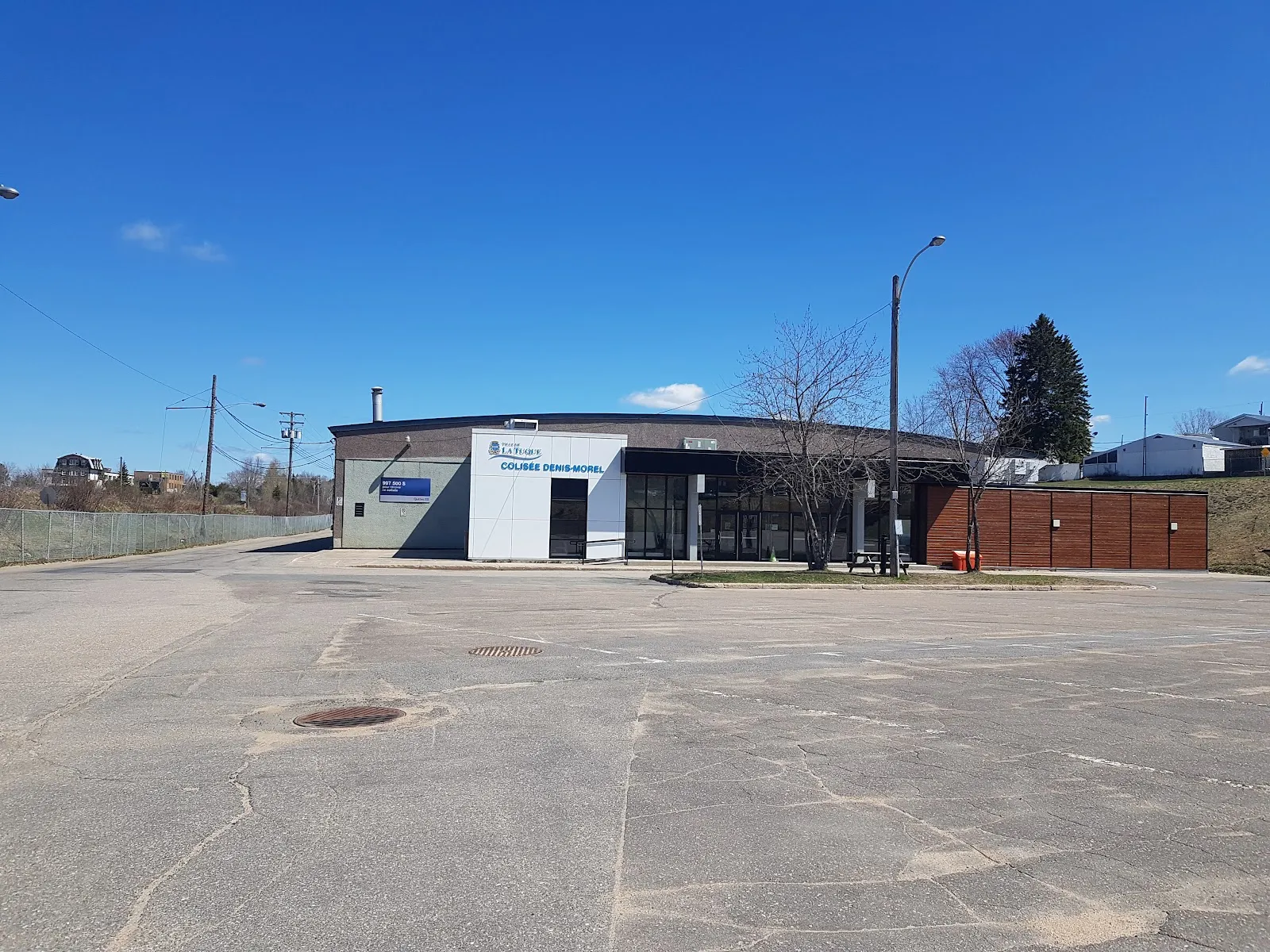 L’entrée du Colisée Denis-Morel et son enseigne, vues de l’autre côté du stationnement par temps clair. — Colisée Denis-Morel