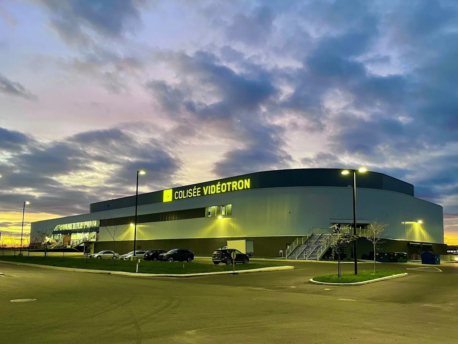 El Colisée Vidéotron al atardecer, con su largo muro gris iluminado bajo el letrero verde de Colisée Vidéotron. — Colisée Vidéotron