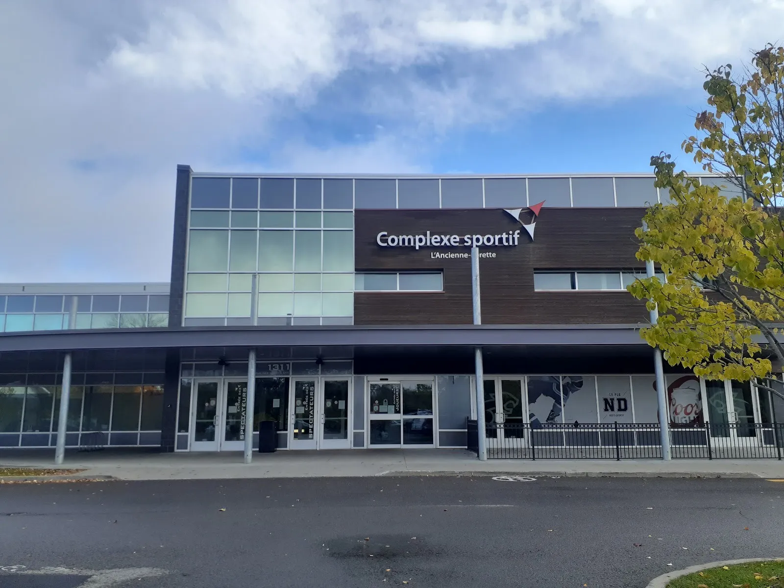 La fachada de vidrio y madera del Complexe sportif en L'Ancienne-Lorette, en 1311 rue des Loisirs Est, bajo su letrero con el nombre — Complexe sportif Bonair