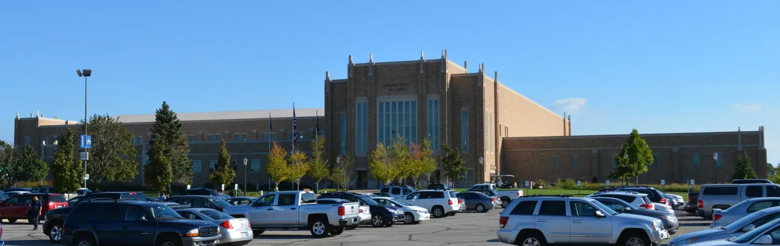 Brick facade of Compton Family Ice Arena with the arena name above the entrance, seen from the campus lot — Compton Family Ice Arena