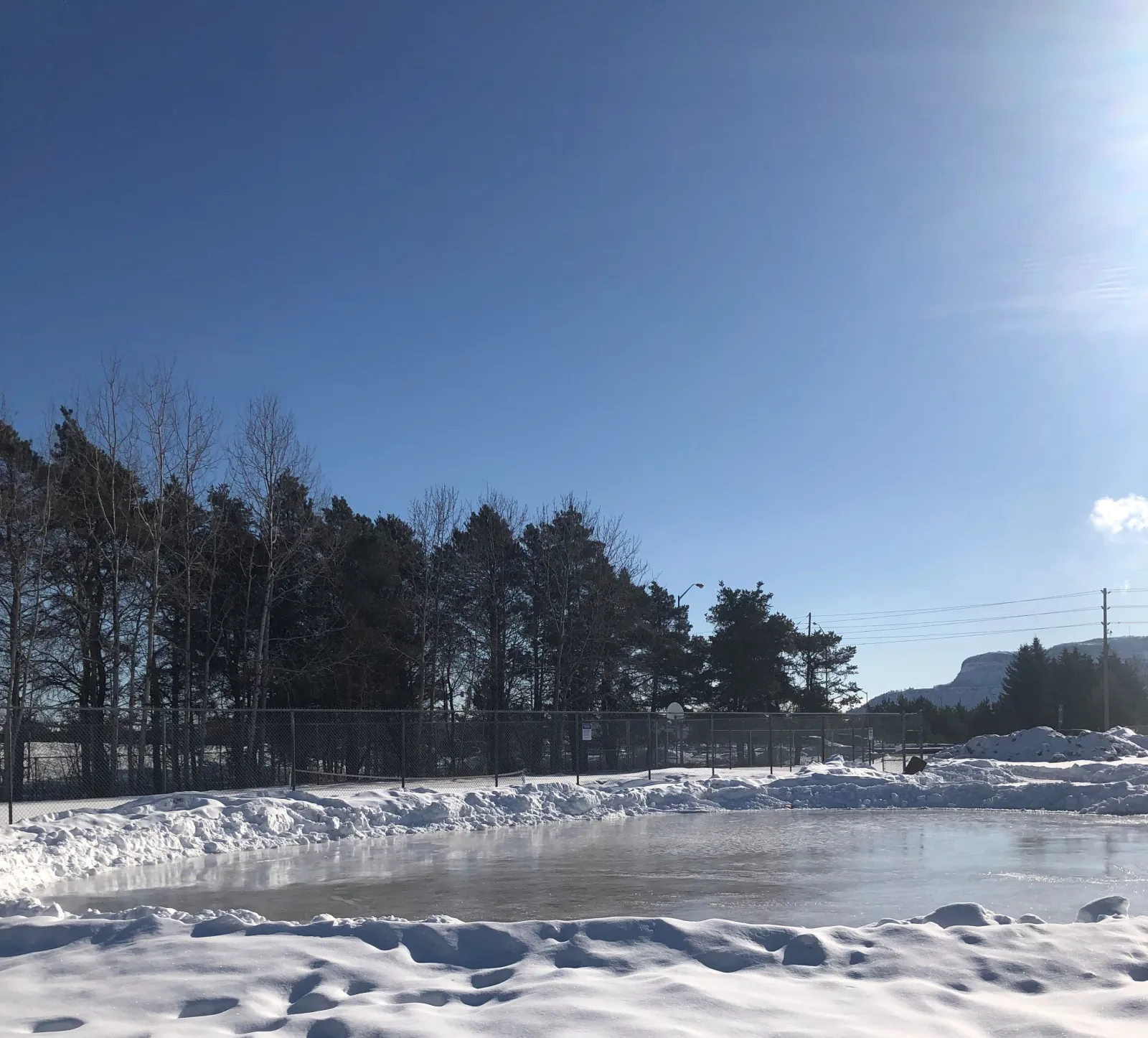 The Confederation Parkette skating pond with spruce trees and the ridge in the distance — Confederation Parkette Skating Pond
