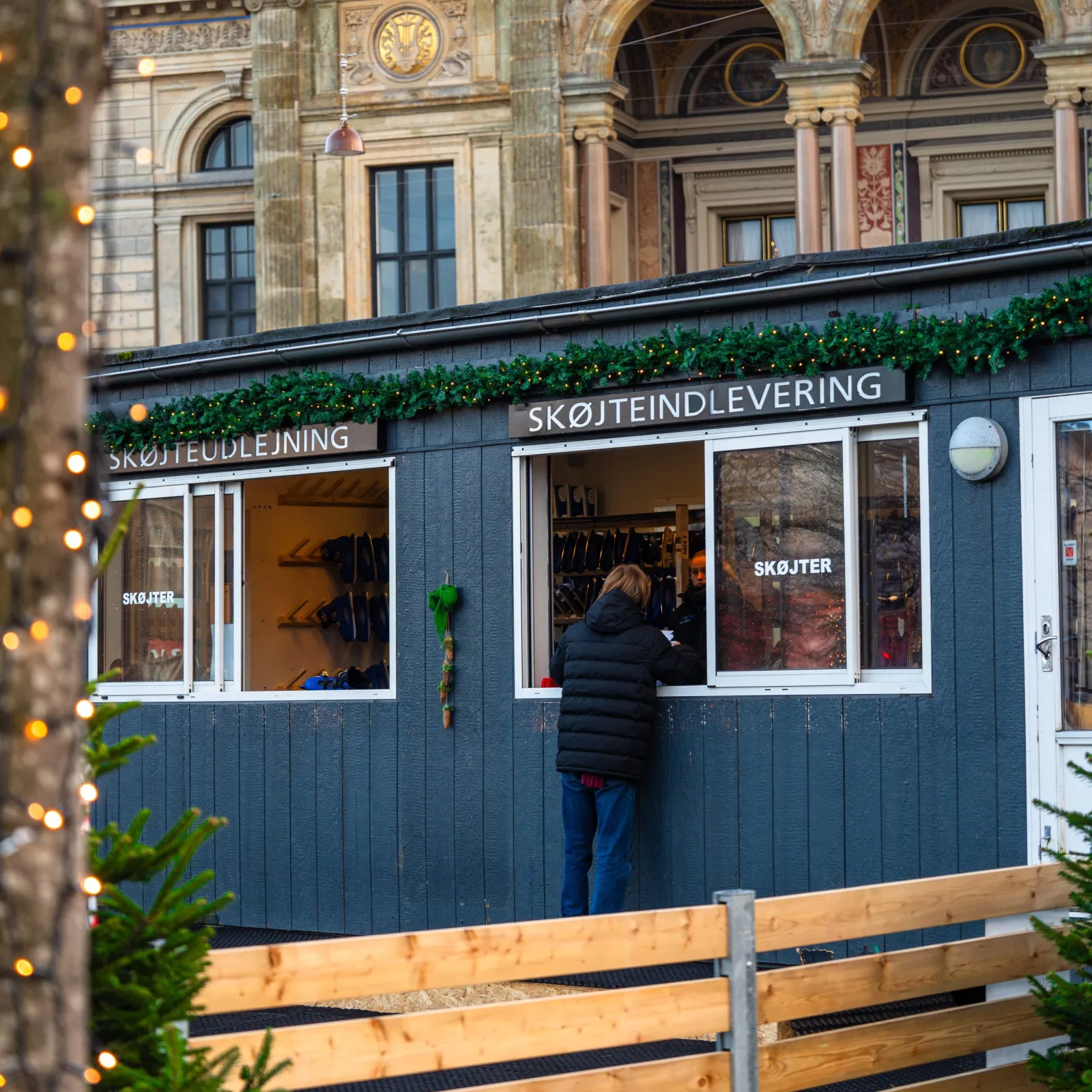 Skøjteudlejningen og skøjteafleveringen i hytter ved banen på Kongens Nytorv med Det Kongelige Teater bagved — Copenhagen Winter Wonderland (Kongens Nytorv)