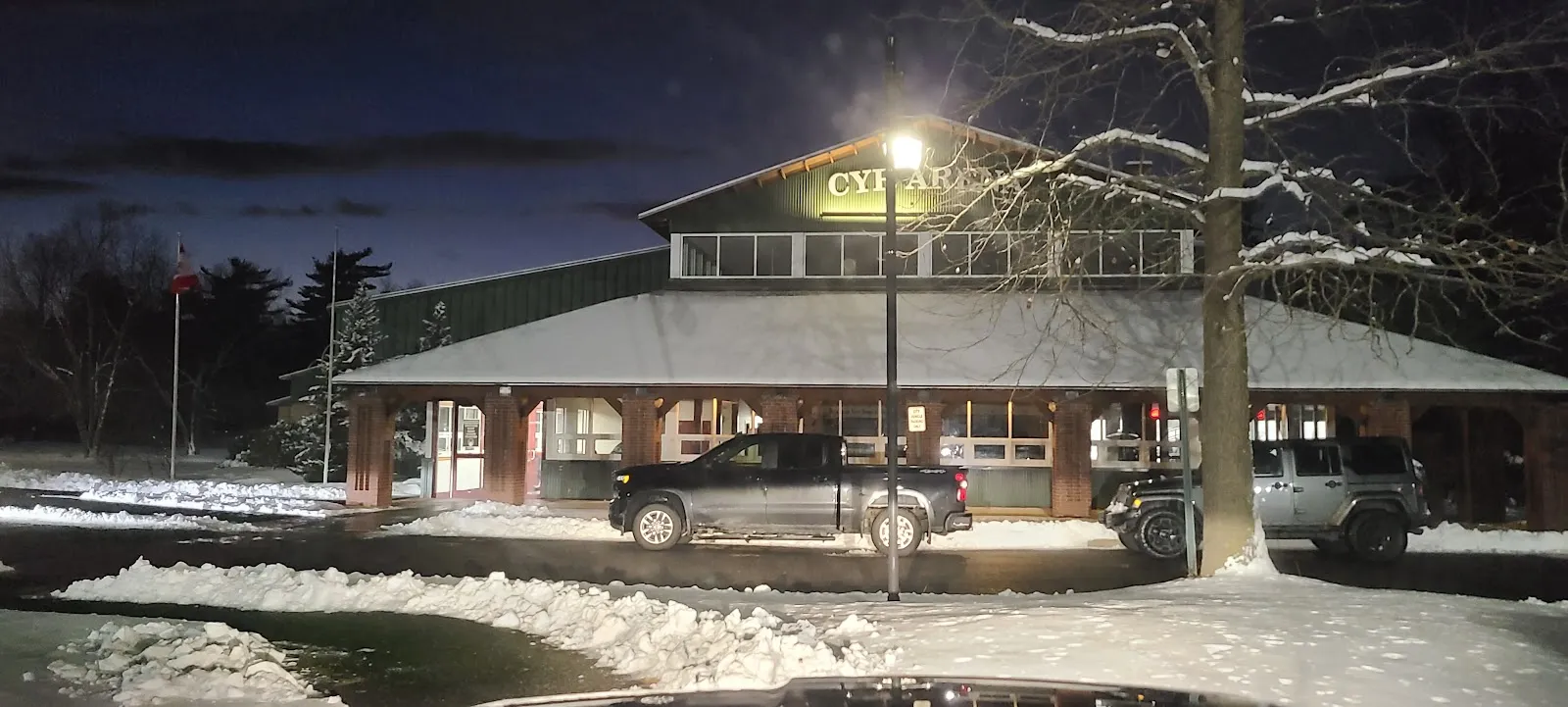 The Cyr Arena building at night with snow on the ground and its lit sign — Cyr Arena