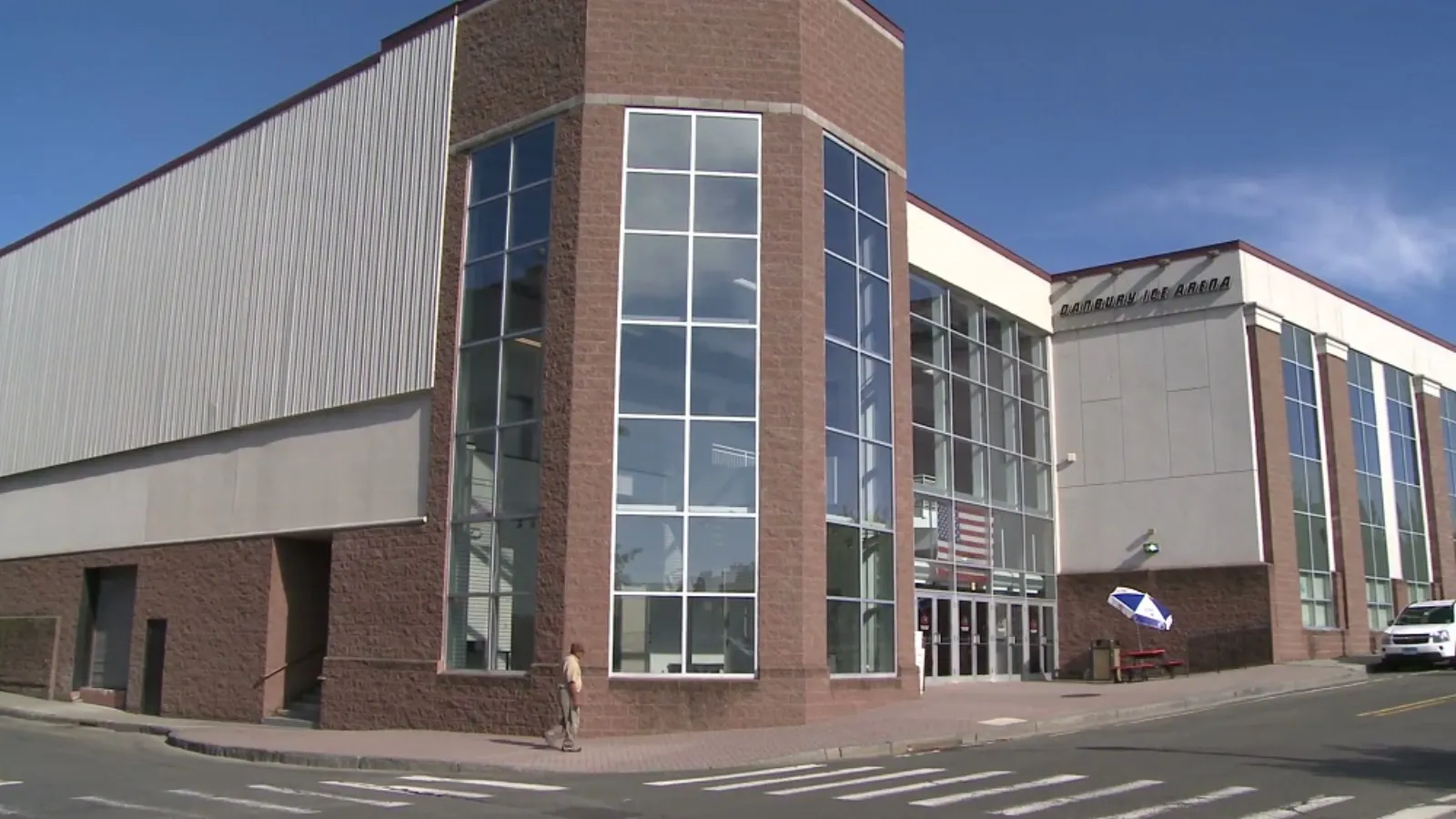 Front corner entrance of Danbury Ice Arena, brick and metal-panel building with "DANBURY ICE ARENA" lettering above the glass entry doors. — Danbury Ice Arena