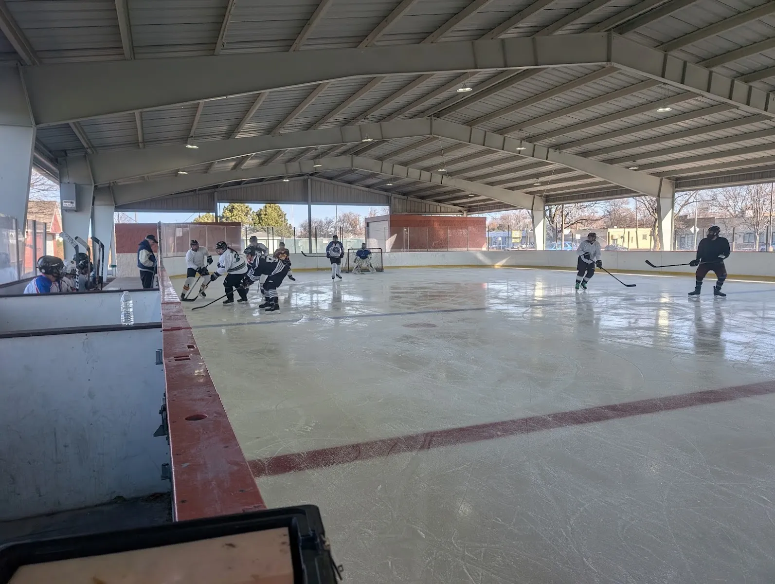 Players at the far end of the covered open-sided rink, with a long red line across the ice — Daniel V. Capuano Ice Rink