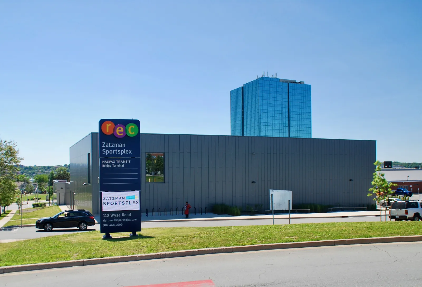 El edificio del Zatzman Sportsplex desde el estacionamiento, con su pilón que dice Zatzman Sportsplex, 110 Wyse Road, y el edificio de la Bridge Terminal de Halifax Transit detrás. — Zatzman Sportsplex