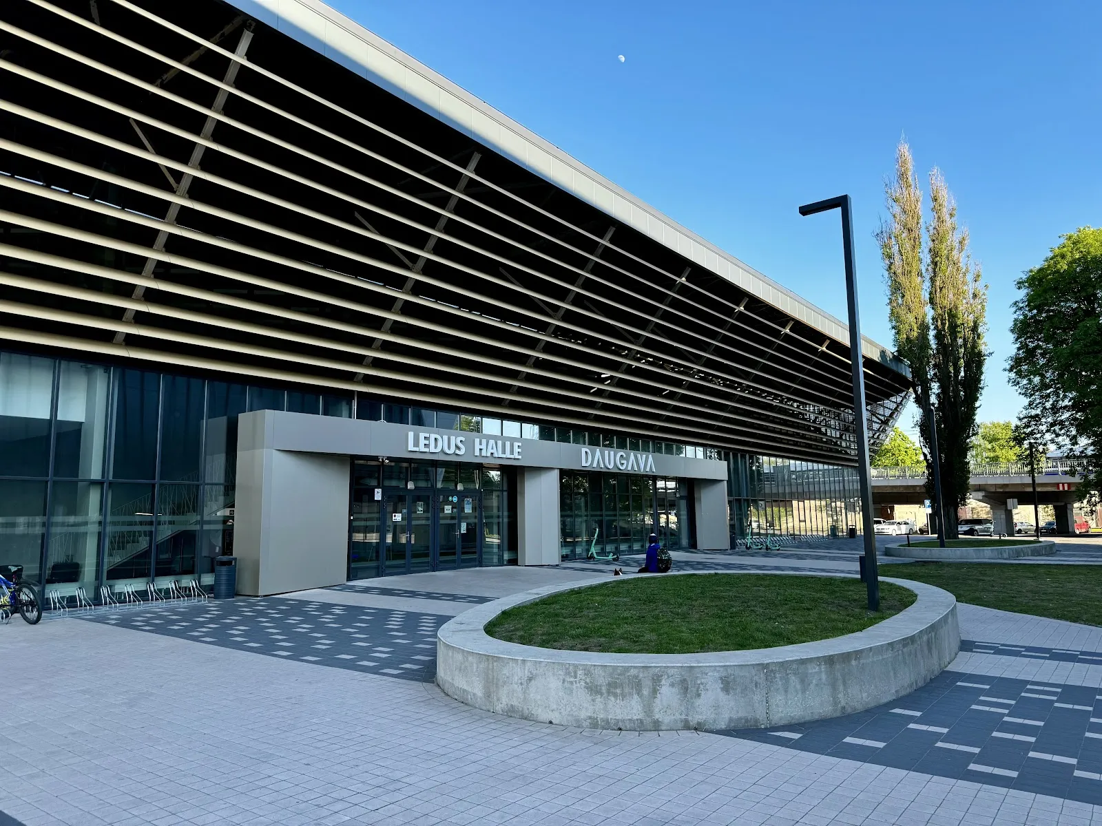 Daugavas ledus halles ieejas fasāde ar koka izskata latu jumta malu un uzrakstu LEDUS HALLE DAUGAVA virs durvīm. – Daugavas ledus halle