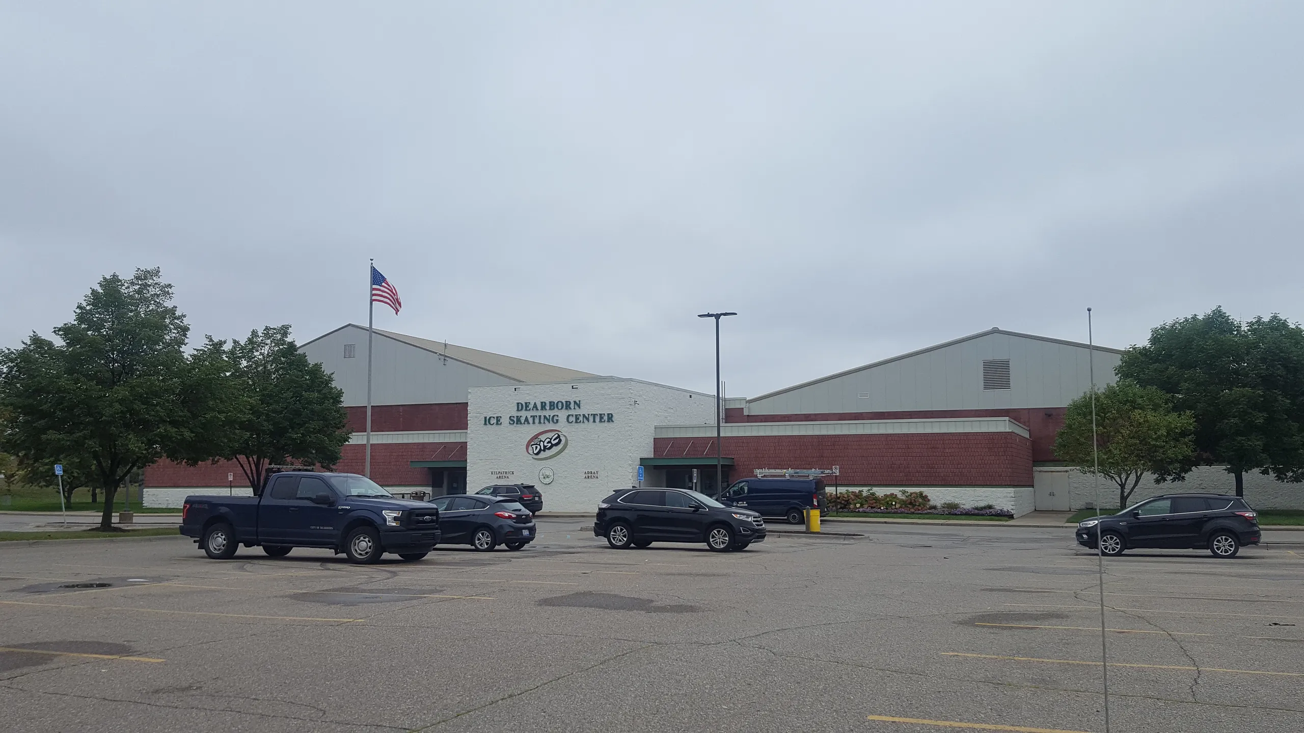 Autos en el estacionamiento bajo los techos a dos aguas de la arena — Dearborn Ice Skating Center