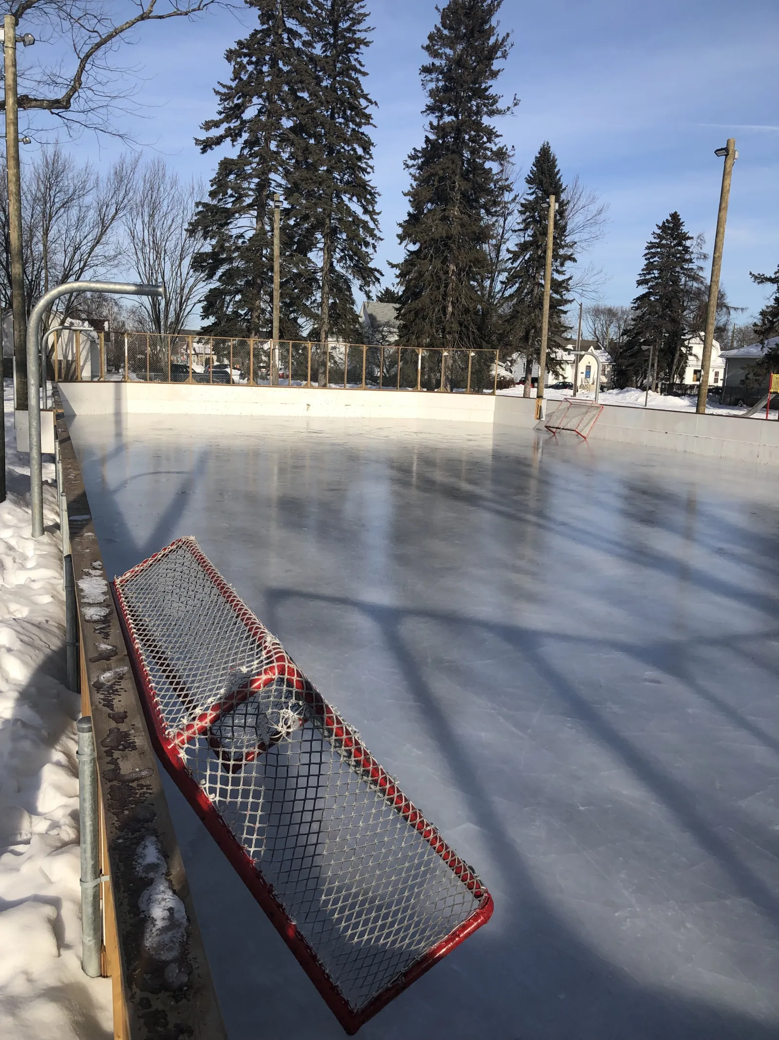 La pista con vallas de Dease Park con una portería en el extremo y hielo despejado — Dease Park Outdoor Rink