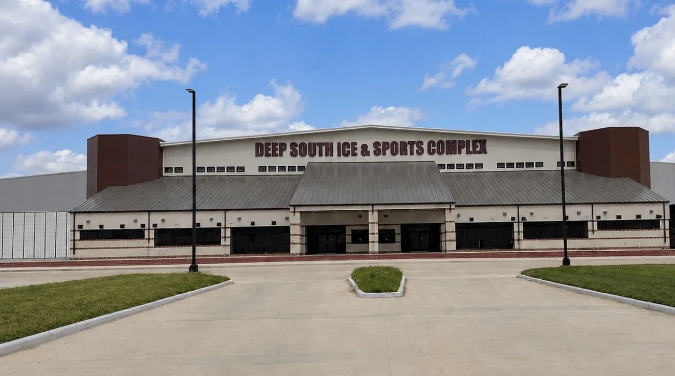 The front of the Deep South Ice and Sports Complex with its name across the cream facade and the empty forecourt in front — Deep South Ice and Sports Complex
