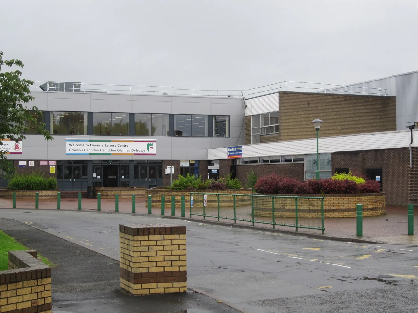 The entrance front of Deeside Leisure Centre, with its bilingual Welcome to Deeside Leisure Centre sign over the glazed doors. — Deeside Ice Arena