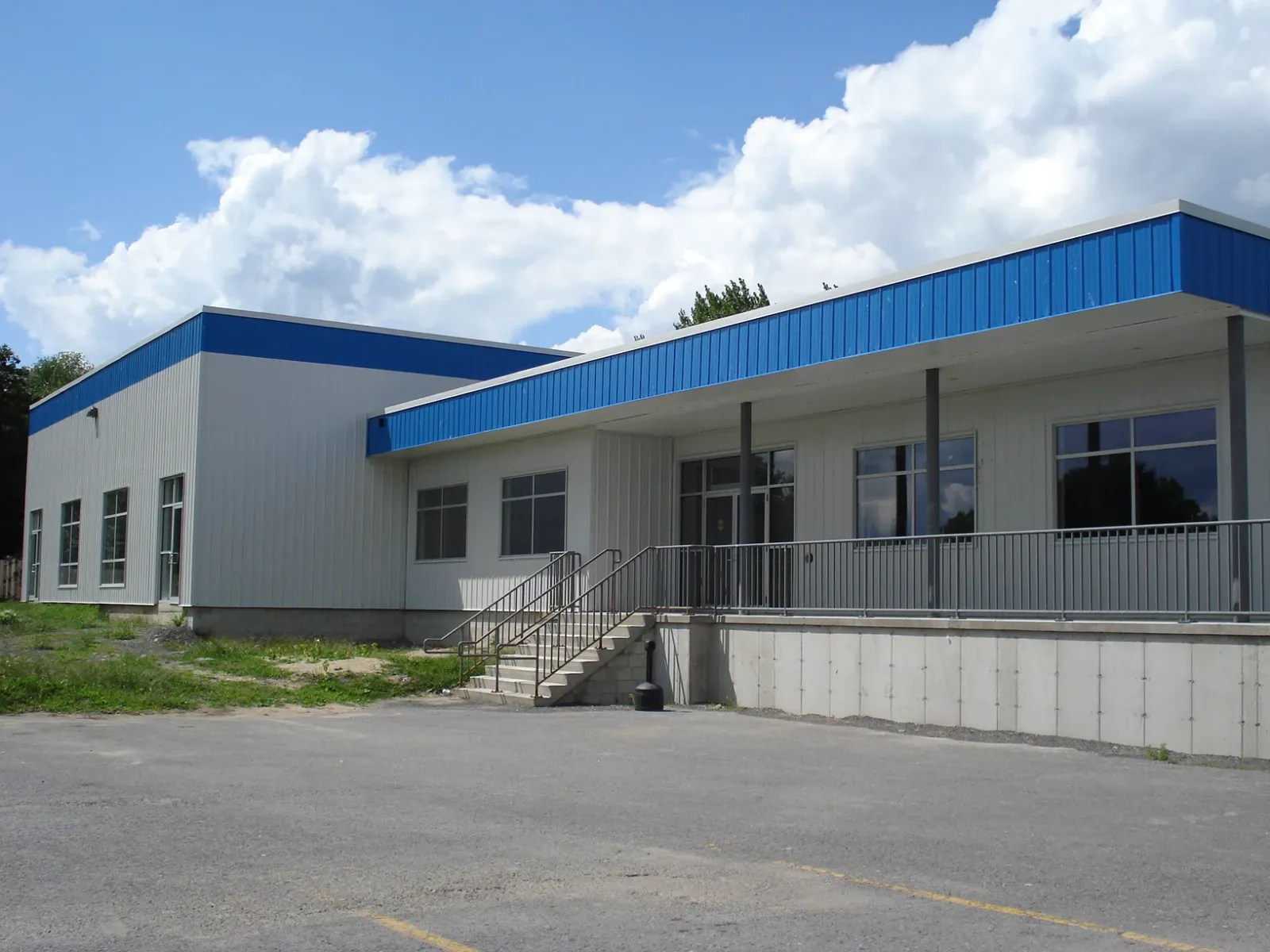 El ala de entrada con detalles azules del Deseronto Community Centre, con sus escalones y barandal frente al estacionamiento. — Deseronto Community Centre