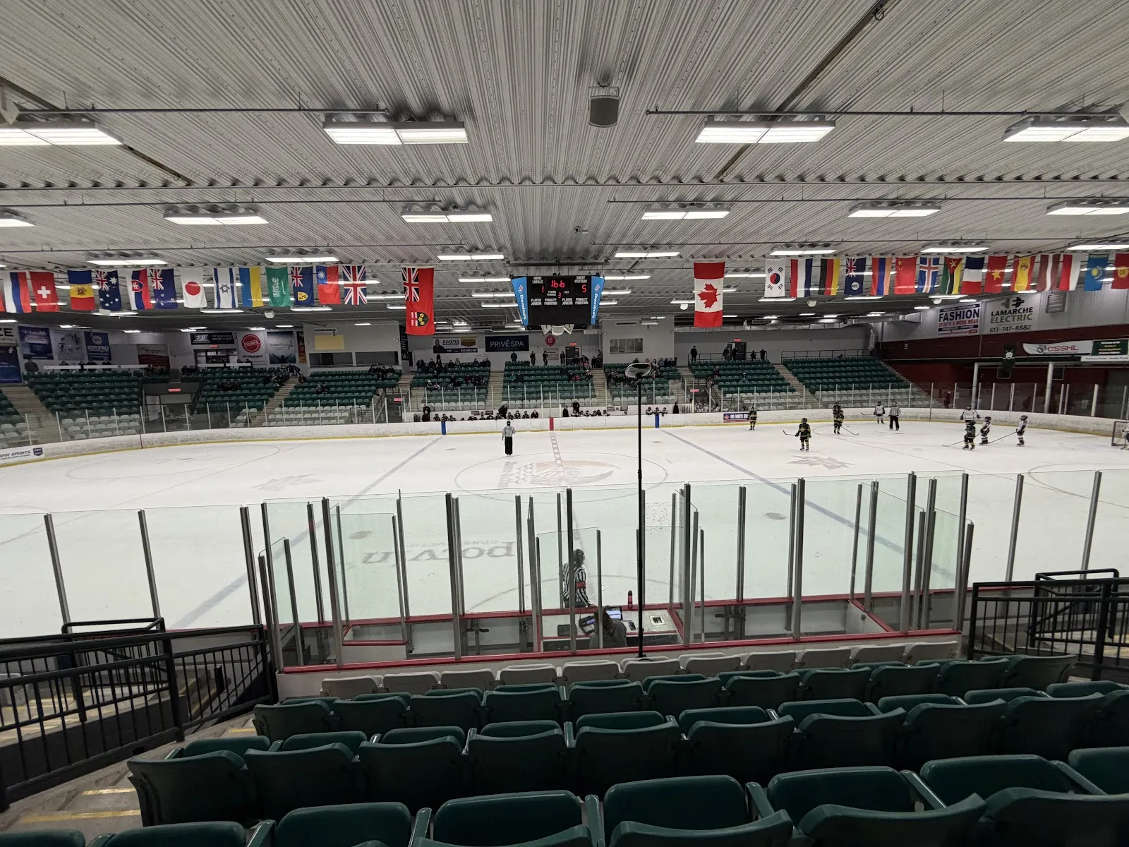 La pista principal desde los asientos verdes, con una hilera de banderas internacionales a lo largo de la pared del fondo. — Desjardins Centre (Rockland)