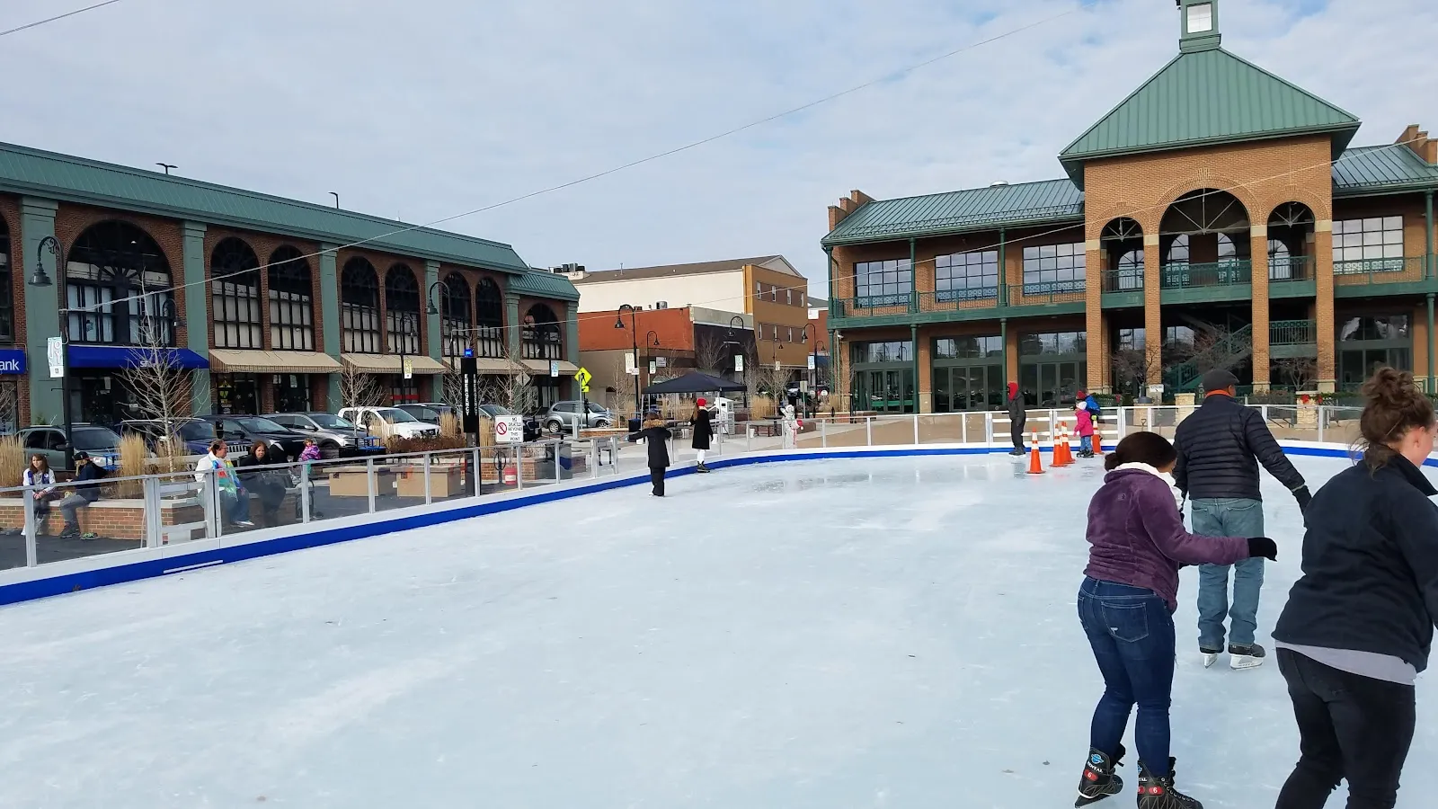 Patinadores en la pista del centro de Cuyahoga Falls, junto a los edificios de Front Street — Downtown Cuyahoga Falls Ice Skating Rink