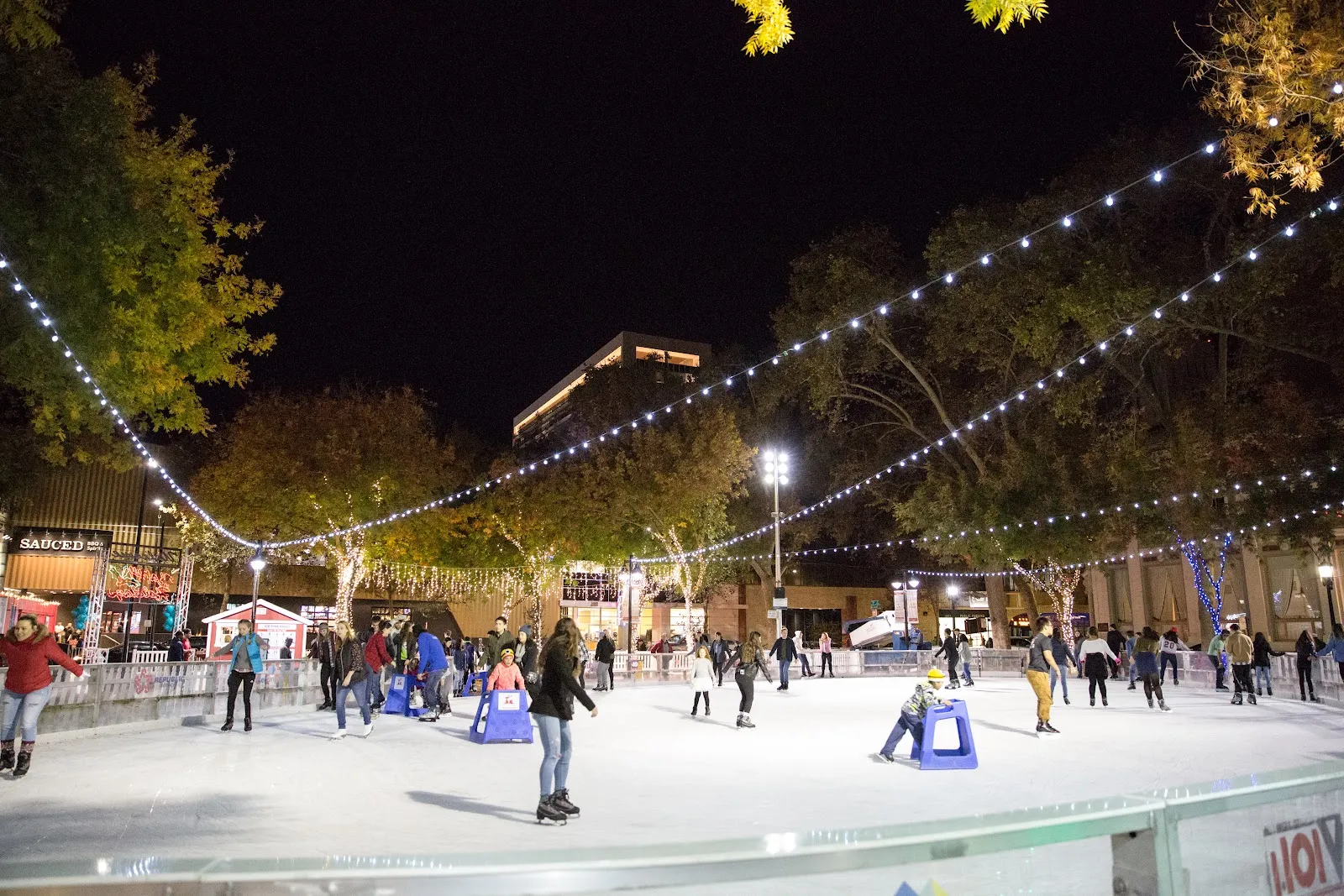 La Downtown Sacramento Ice Rink de noche, con tiras de luces sobre la pista en Ali Youssefi Square (foto del listado de Google Maps) — Downtown Sacramento Ice Rink