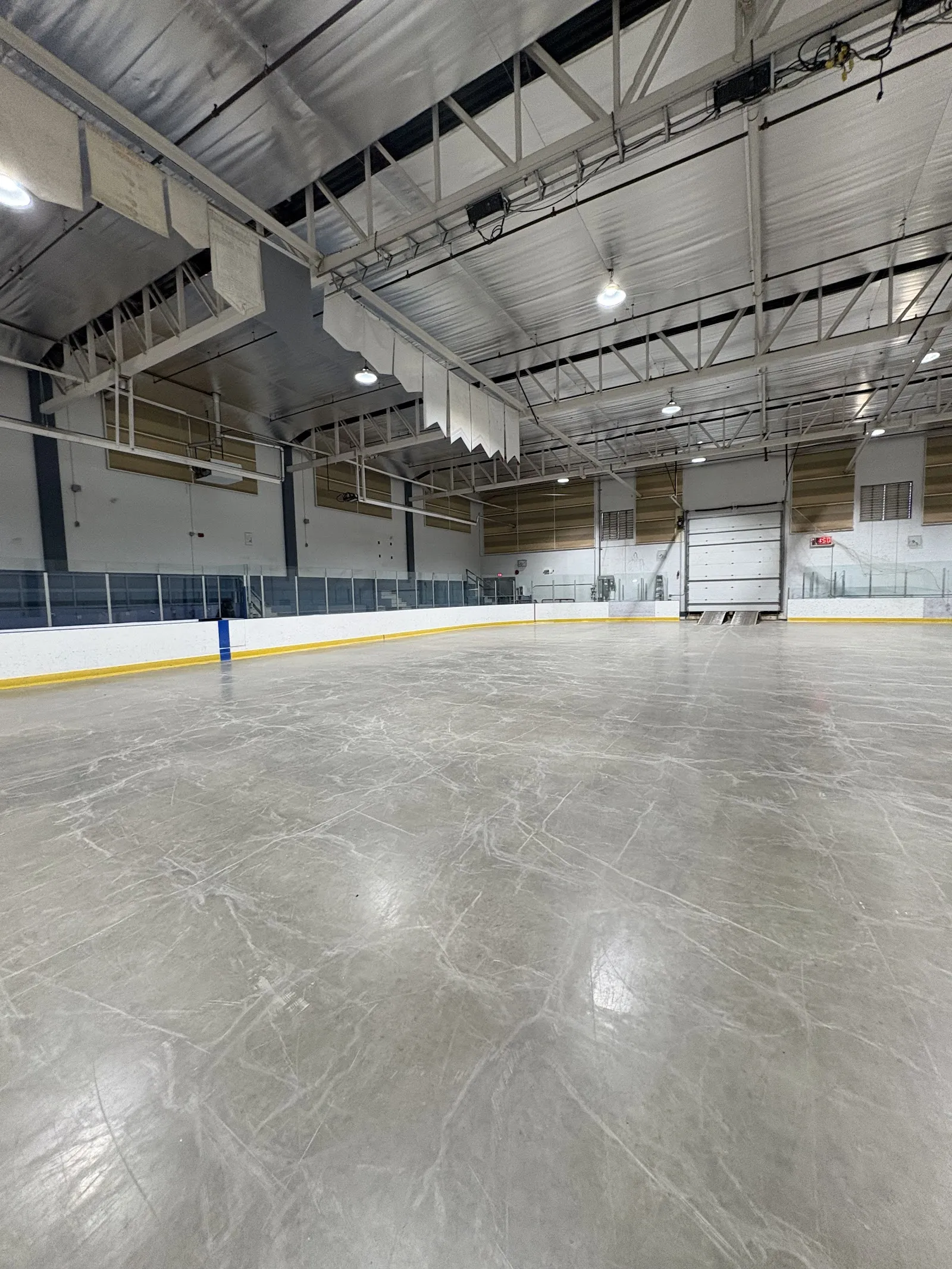 An empty, freshly scored ice sheet at the Dr. Duncan Murray Recreation Centre in Hinton, with the boards, glass and steel roof trusses around it. — Dr. Duncan Murray Recreation Centre