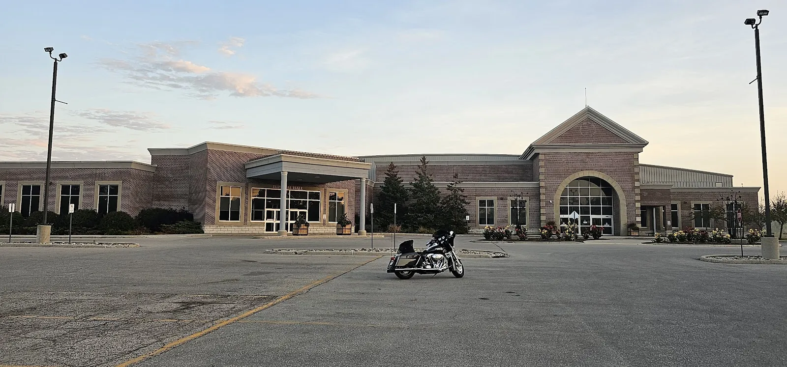 The brick East Elgin Community Complex seen across its parking lot, with a gabled arched entrance on the right, a covered entrance marked Imperial Hall on the left and the arena roof behind. — East Elgin Community Complex (Aylmer)