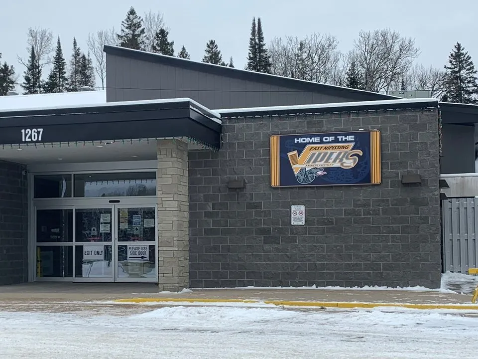 The street entrance of the community centre under its low roof, with the civic number 1267 on the wall and a Home of the Vipers sign. — East Ferris Community Centre (Astorville)