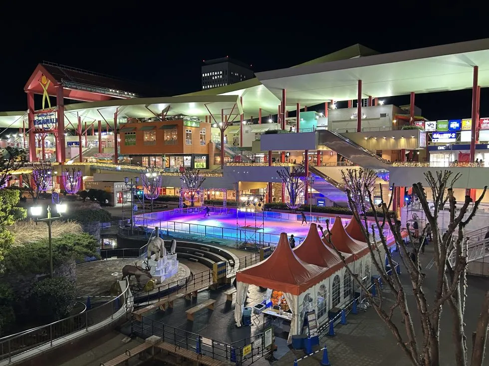 The lit pop-up rink and red ticket tents among the shops and walkways of central Ebina at night. — Ebina Central Park Wakuwaku Ice World