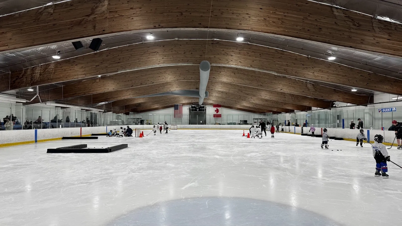 Una pista de Eddie Edgar de extremo a extremo bajo el techo curvo de madera, con una sesión juvenil de aprende a jugar repartida por el hielo — Eddie Edgar Ice Arena