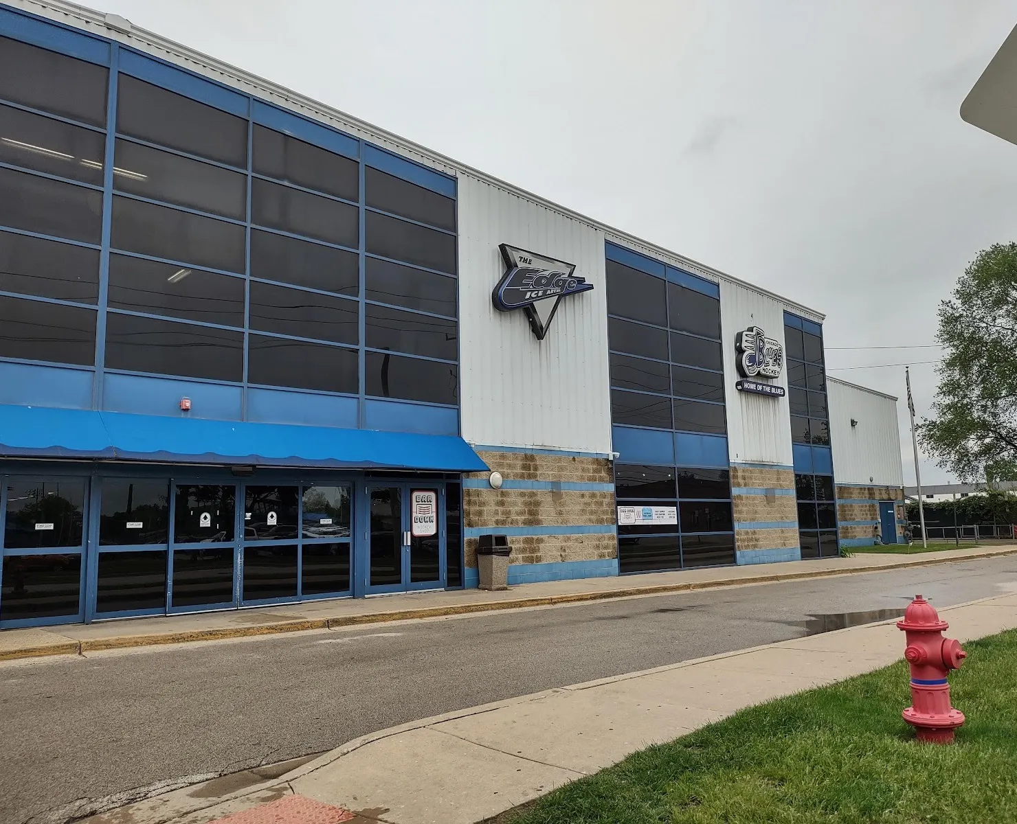 The blue and white front of The Edge Ice Arena on John Street in Bensenville, with its Edge logo above the entrance awning — The Edge on John St (Bensenville)