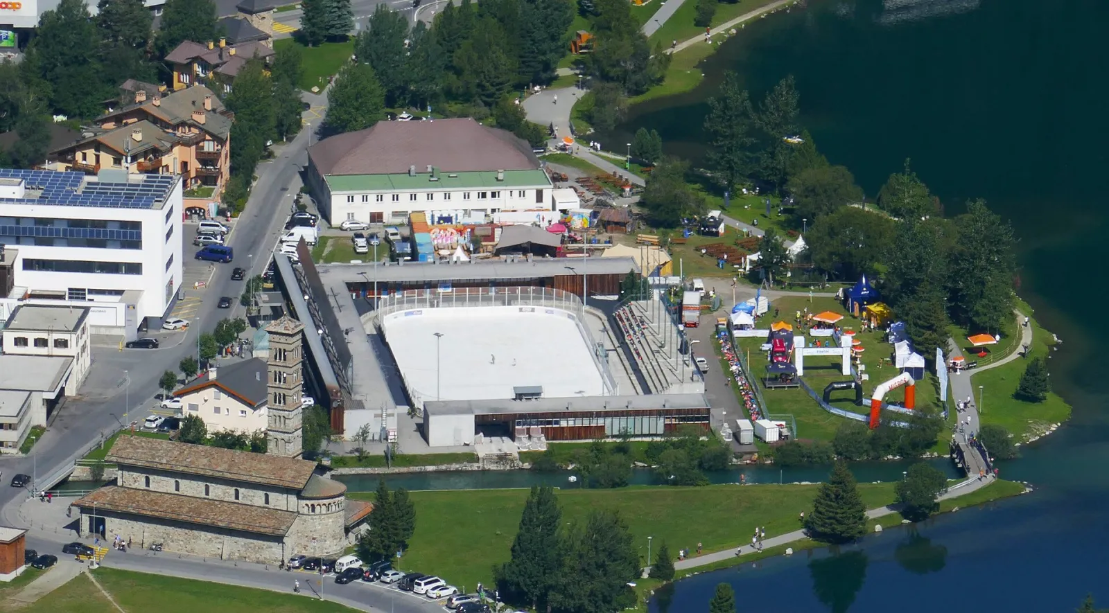Luftaufnahme der Eisarena Ludains in St. Moritz Bad am Inn und am See, mit der weissen Eisfläche in der offenen Arena – Eisarena Ludains