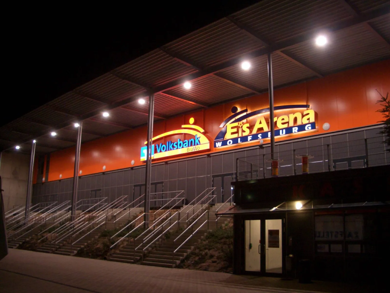 The EisArena Wolfsburg at night with its illuminated lettering above the stairs. — EisArena Wolfsburg